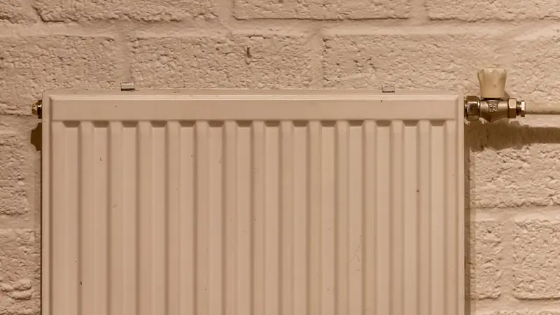 Radiador de calefacción blanco sobre una pared de ladrillo pintada